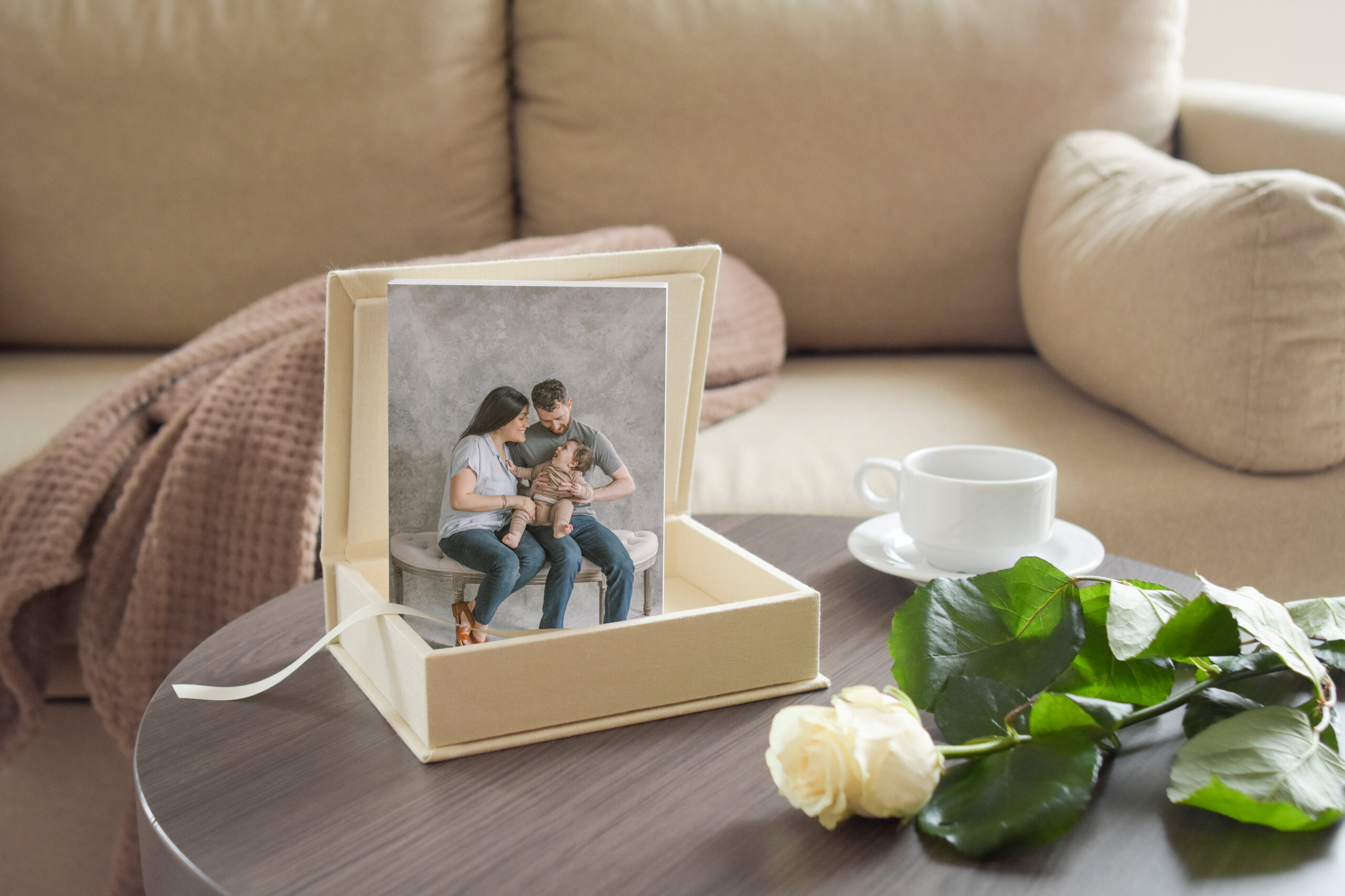 A framed photo of a couple with a pet on a wooden table, accompanied by a rose and a cup of coffee.