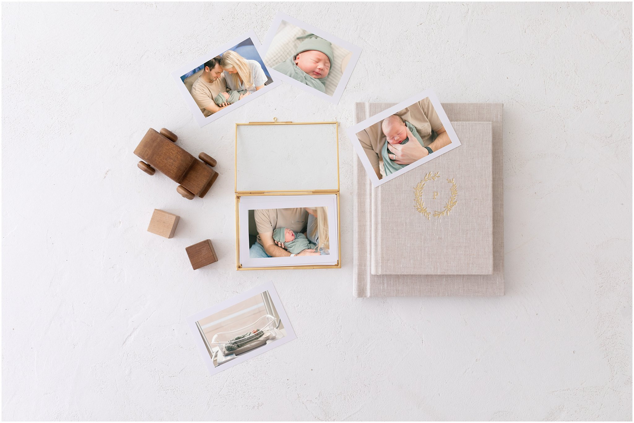 Flat lay of a journal, photo frames, wooden blocks, and printed photos on a light surface.