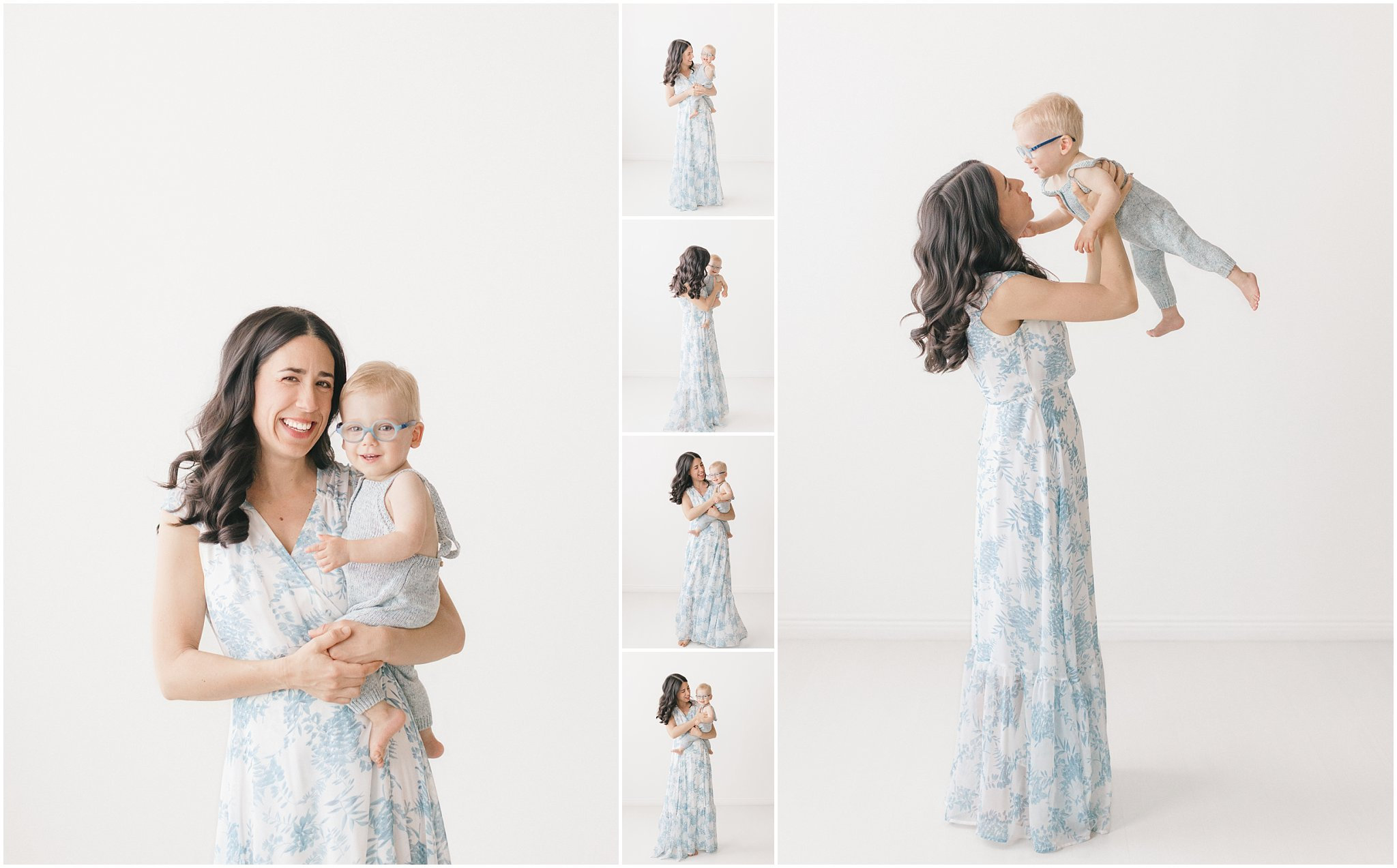 Mother in a floral dress holding an infant, posing joyfully against a white backdrop.