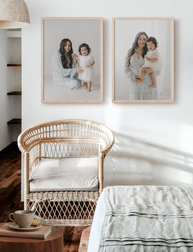 Cozy room with rattan chair, framed portraits of a mother and child on the wall, and neutral decor.