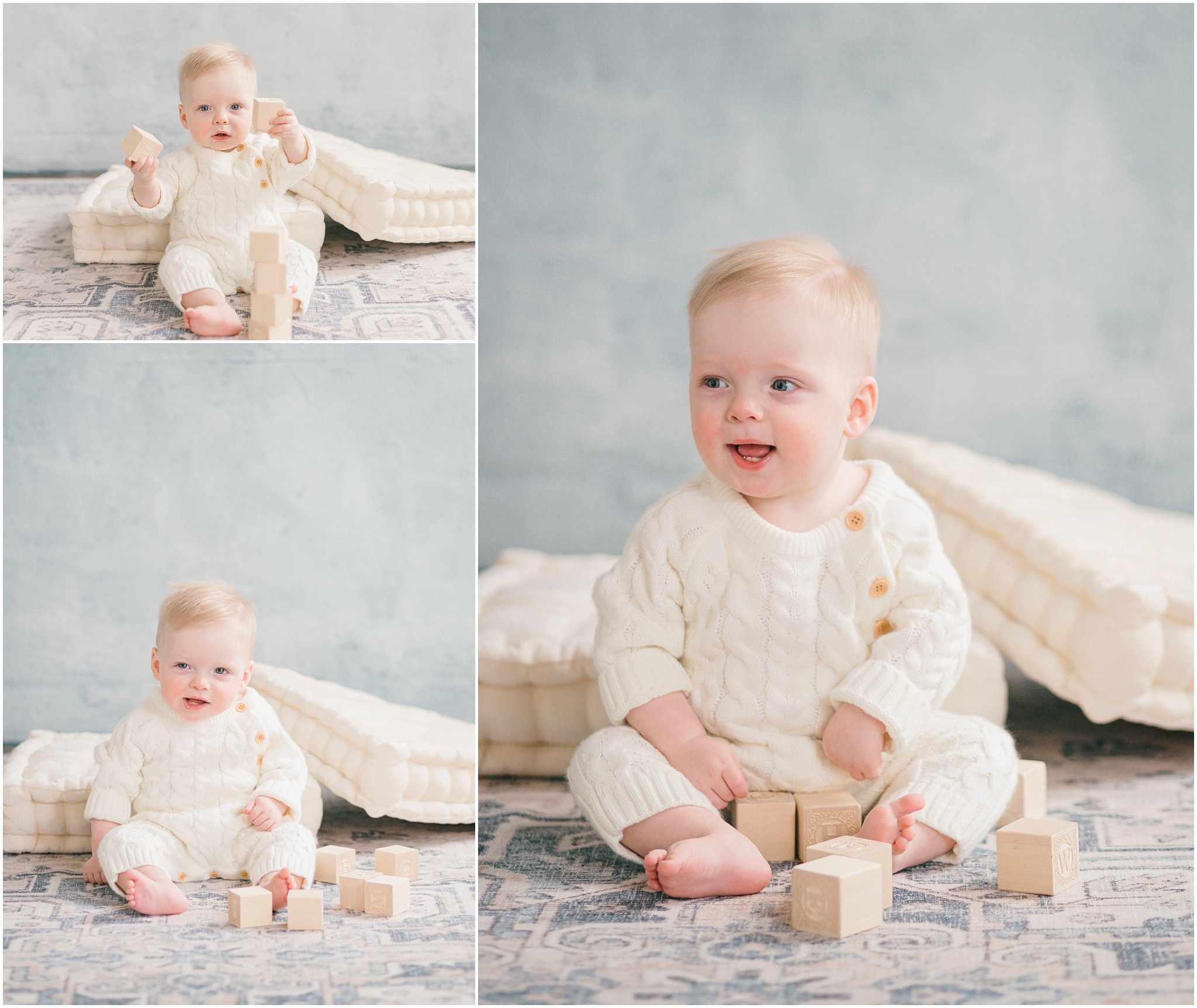 Baby in a cream outfit sitting on a patterned rug with wooden blocks, against a soft blue background.