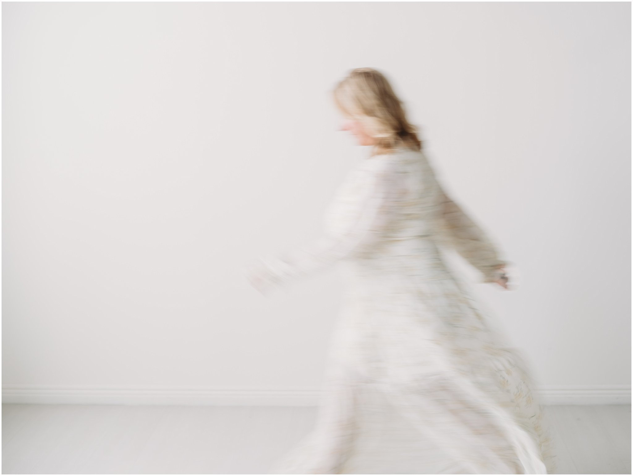 Person in flowing white attire moving in a minimalist, blurred setting.