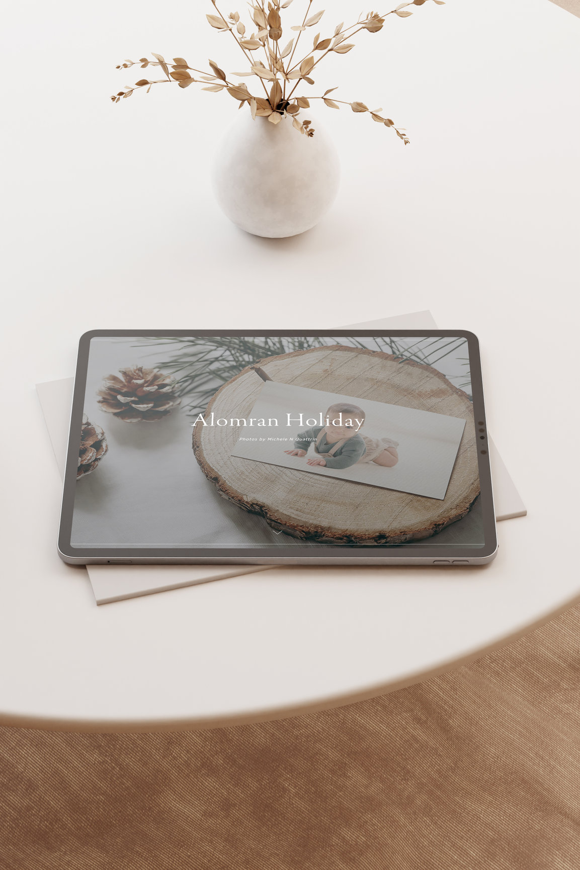 Tablet on a table displaying a photo with dried flowers in a vase nearby.