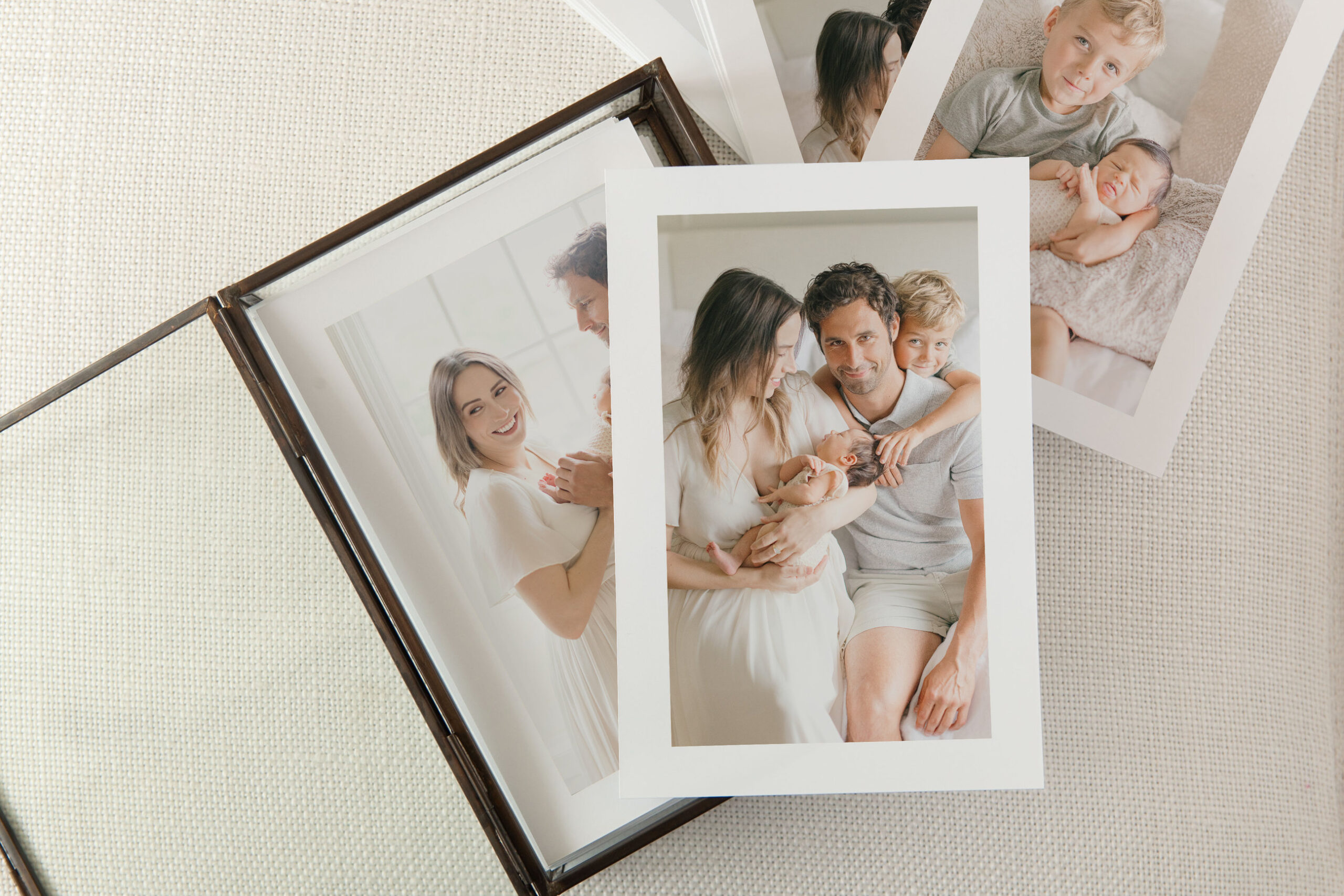 Family photo prints scattered on a surface beside a box.