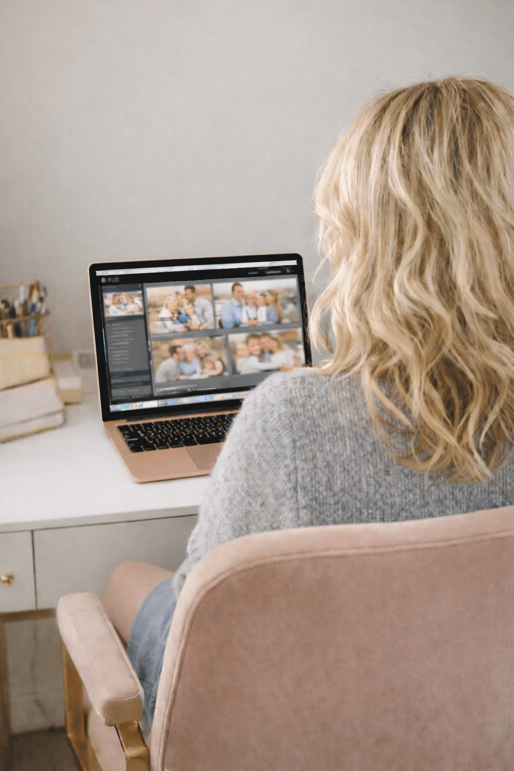 Person with blonde hair using a laptop at a white desk with stationery items.