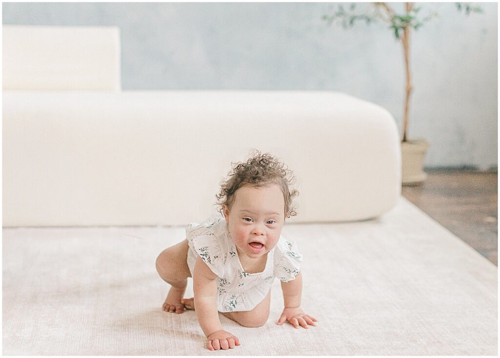 Baby crawling on a white studio bed during a baby's first year photography session in Minneapolis.