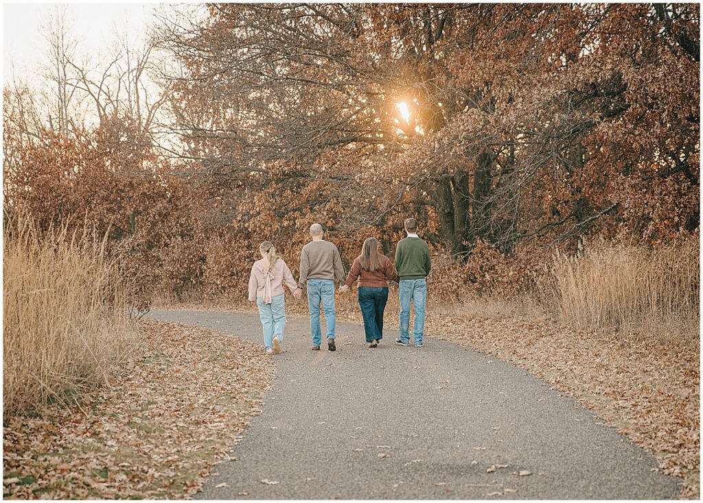 Family walking together on a paved path during fall family photos in Minnesota.