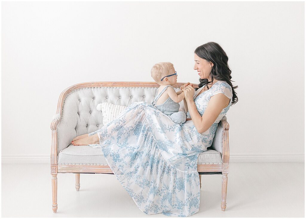 Twin Cities motherhood photographer studio session with mom and toddler sitting together on a soft gray couch