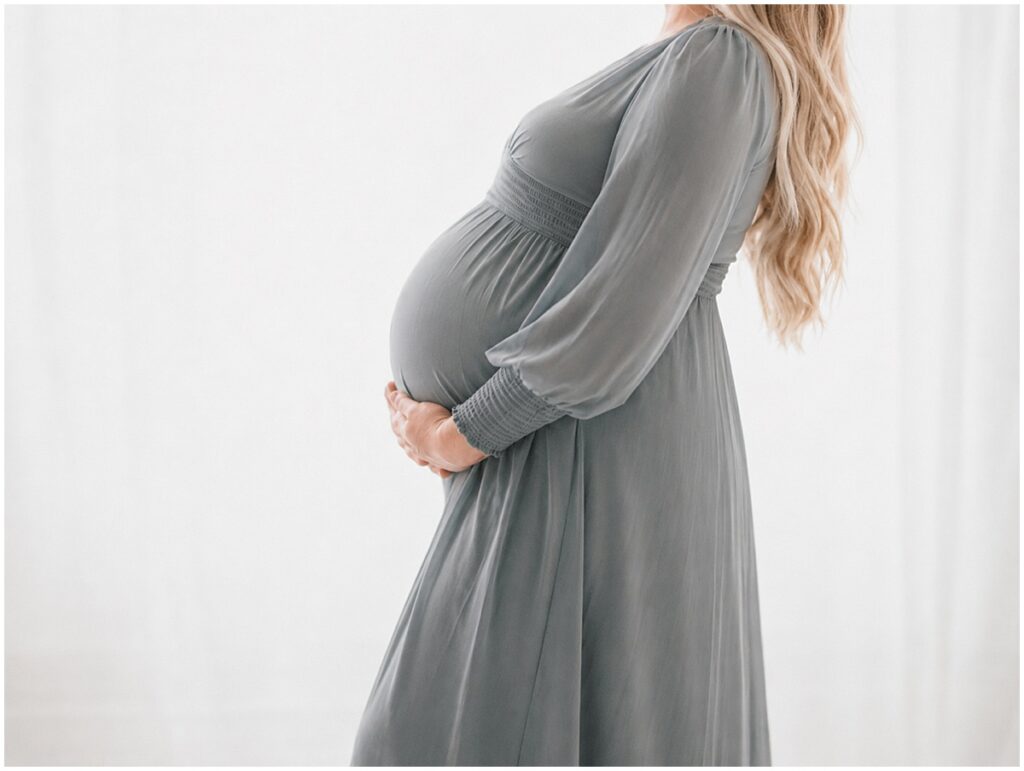 Pregnant mother in a slate blue dress during an indoor maternity session in St. Paul, Minnesota