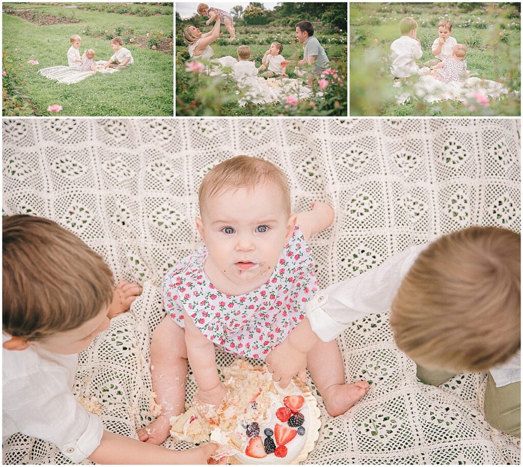 Outdoor cake smash with a one year old baby girl sharing cake and fresh berries with her two older brothers