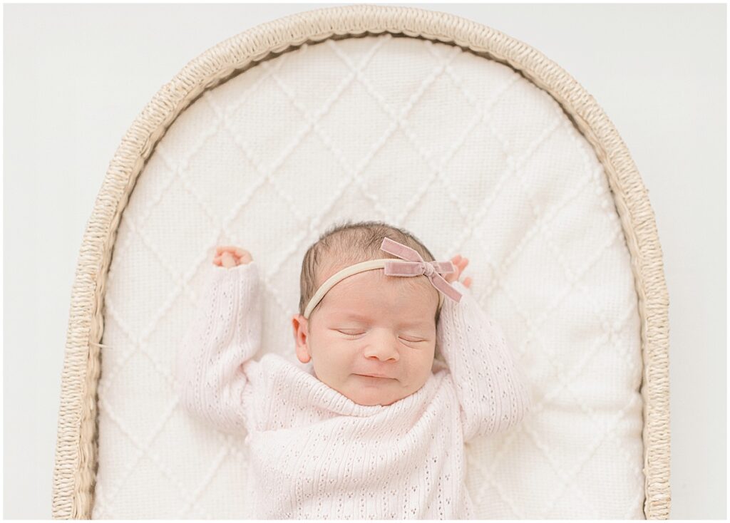 Sleeping newborn baby in a pink outfit on a neutral studio blanket during a Minneapolis newborn session with mQn Photography