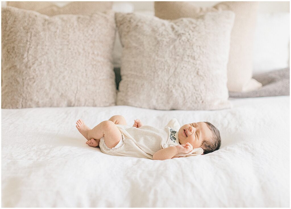 Newborn baby lying on a white bed in a cream knit outfit during an In-Home Newborn Photography session in North Oaks.