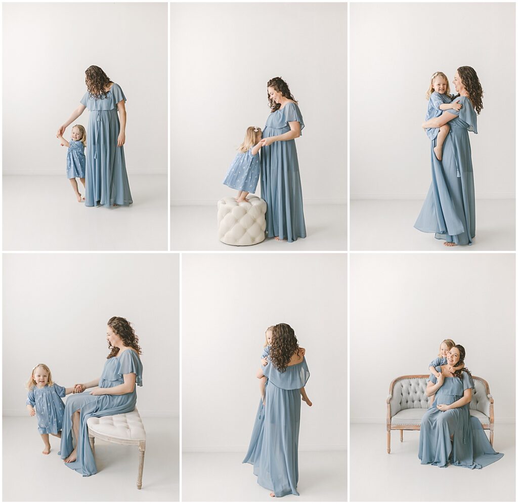 Pregnant mother in a blue dress posing with her toddler daughter in a bright studio.