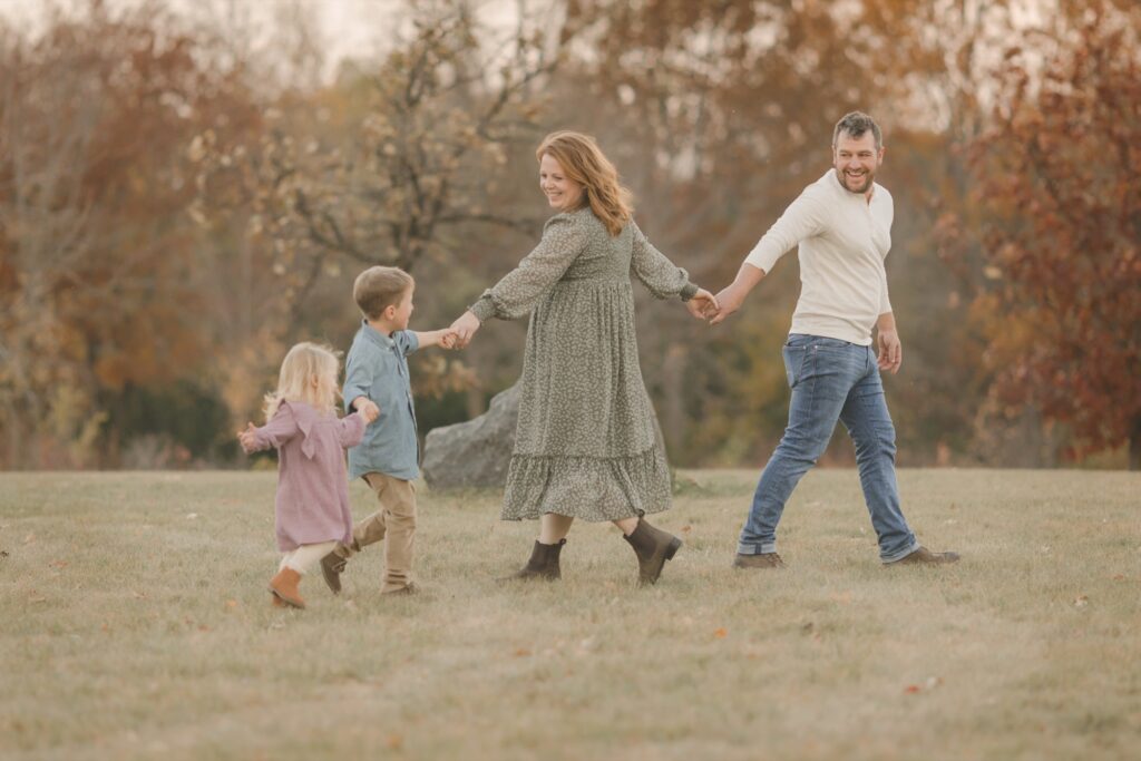 Kids laughing while dancing in a circle with their parents, a candid moment for Christmas card photos